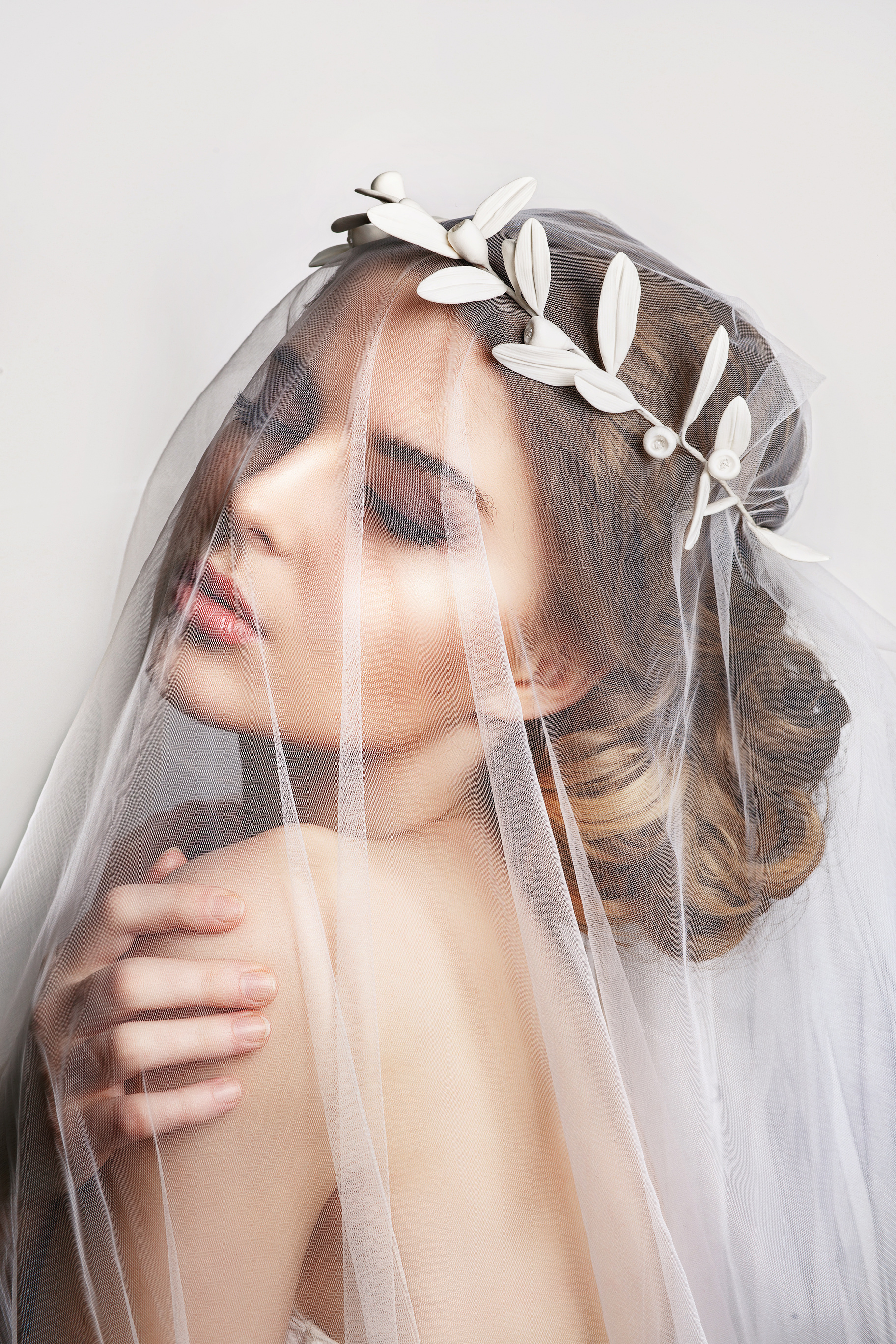 Beautiful bride with fashion wedding hairstyle - on white background. Close-up portrait of young gorgeous bride. Wedding. Beautiful bride portrait with veil over her face